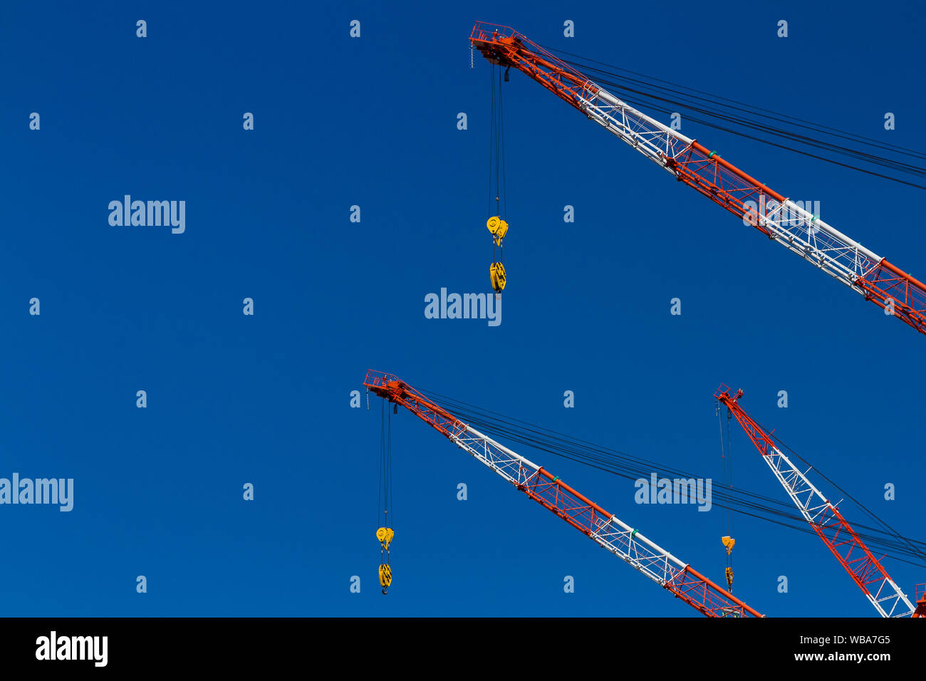 Abstraktes Bild der rot und weiß lackierten Krane der Wippauslegerkräne auf der Baustelle für die Sicherheit in Tokio, Japan. Stockfoto