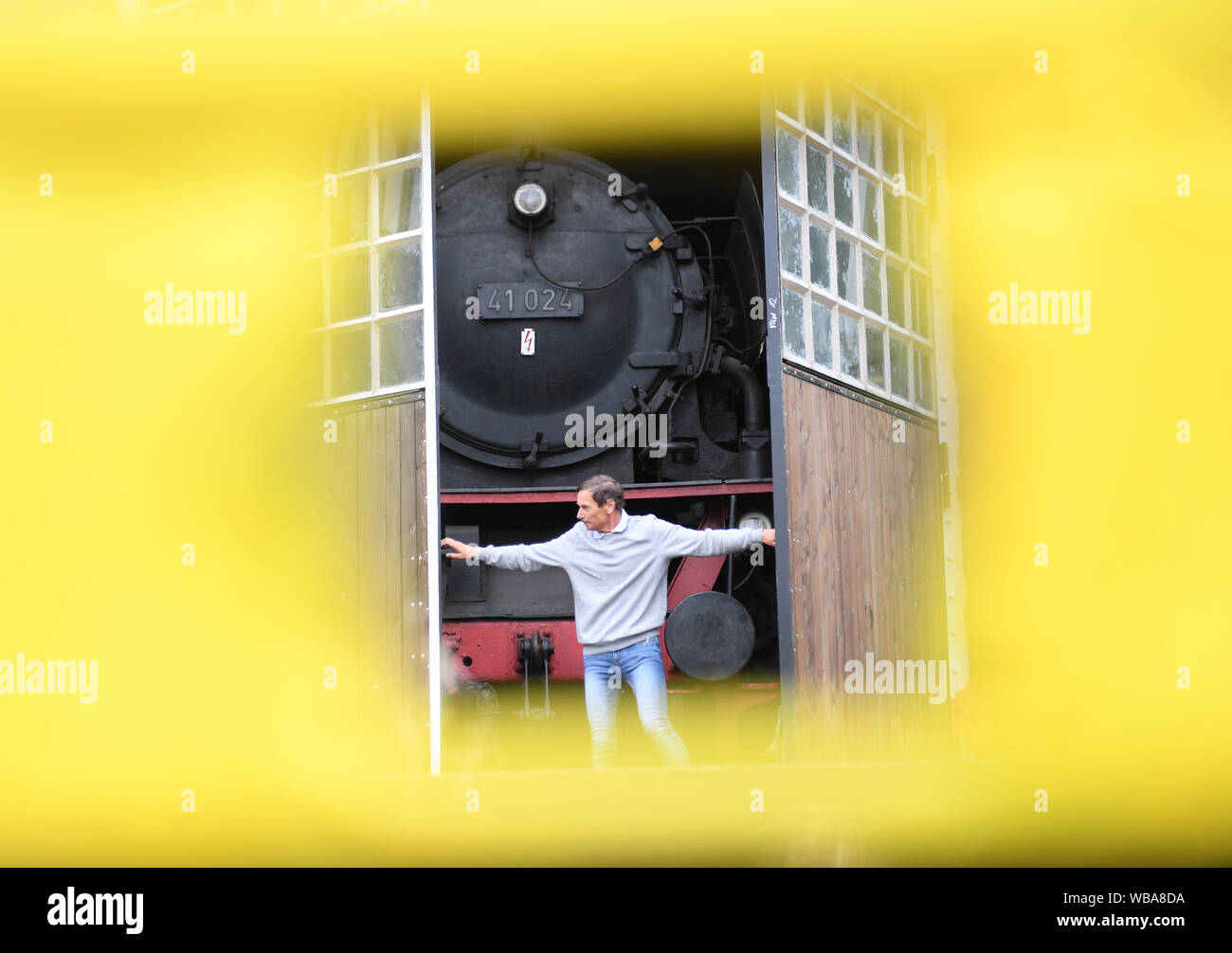 20. August 2019, Hessen, Darmstadt: Uwe Breitmeier, erster Vorsitzender der Eisenbahn Welt Darmstadt-Kranichstein, öffnet ein Tor der Lokschuppen auf dem Freigelände des Museums, hinter dem steht ein Klasse 41 Dampflokomotive. Auf der großen Fläche des ehemaligen Darmstadt rangierbahnhof sie Eisenbahngeschichte erleben können. 1970 von eisenbahnfans gegründet, hat der Verein seit gesammelt und beschafft 45 Lokomotiven, rund 150 Waggons und Maschinen für Reparaturen und Wartung. (Dpa "Eisenbahn Romantik hat seinen Preis - über 50 Museumsbahnen in Deutschland") Foto: Arne Dedert/dpa Stockfoto