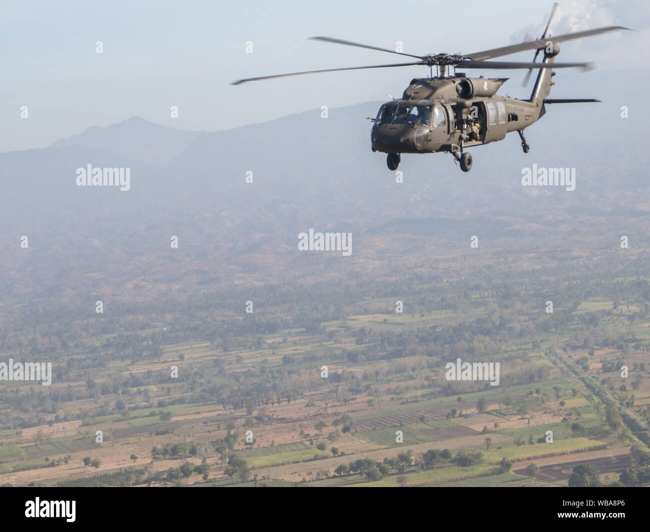 Ein Soldat aus dem 16 Combat Aviation Brigade, schaut aus einem Sikorsky UH-60 Black Hawk bei Garuda Shield 19 23. August 2019, Ost Java, Indonesien. Garuda Shield ist eine jährliche bilaterale militärische Übung gefördert durch die US-Armee Pazifik und jährlich bewirtet durch Tentara Nasional Indonesia. Dieses Jahr zum dreizehnten Iteration von diesem ständigen Bemühen für Frieden und Sicherheit in der Region zu fördern. (U.S. Armee Foto von Pfc. Lawrence Broadnax, 28 Public Affairs Abteilung) Stockfoto