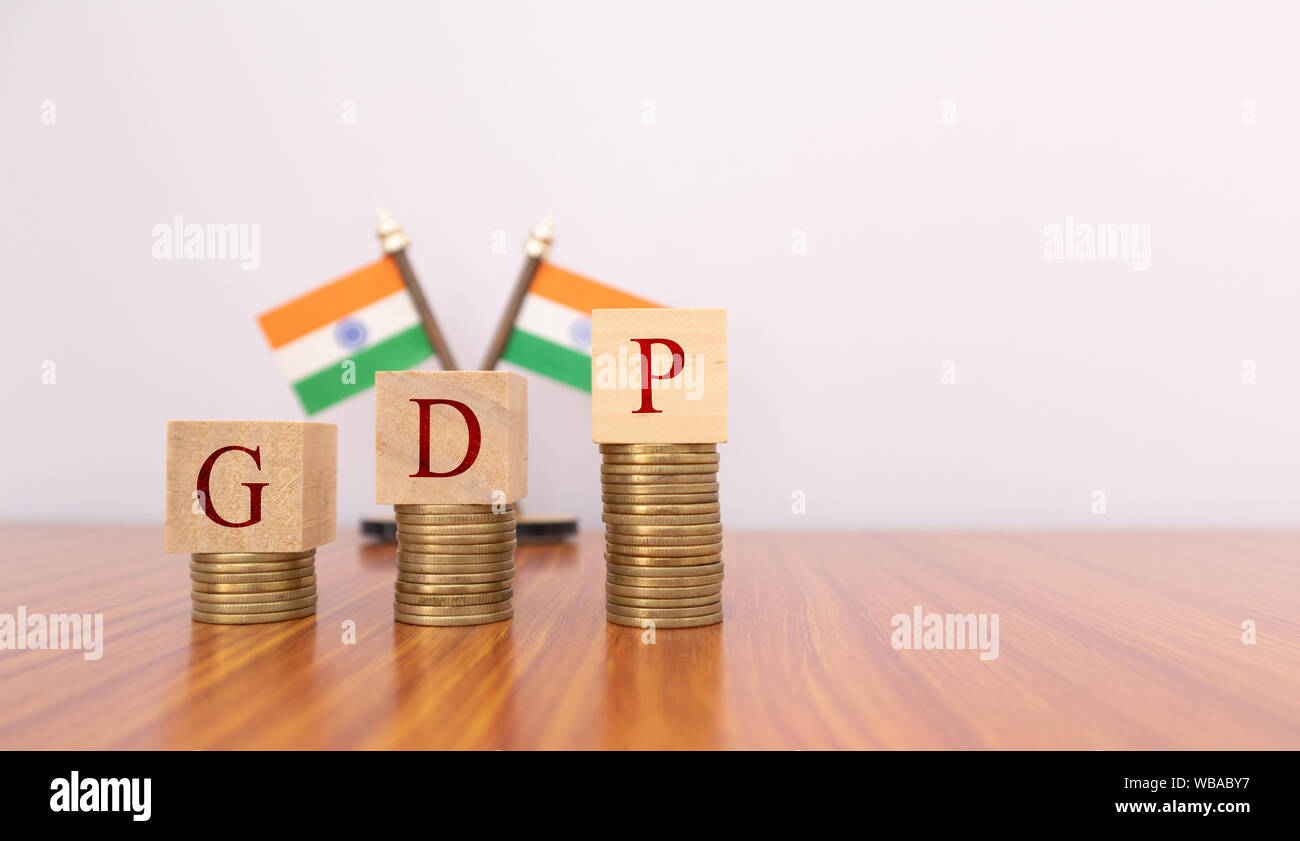 Das BIP oder das Bruttoinlandsprodukt in Holzblock Buchstaben auf Münzen in aufsteigender Reihenfolge mit der indischen Flagge als Hintergrund. Stockfoto