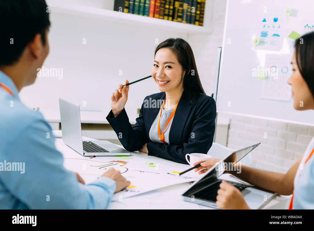 Asiatische ausgereifte lächelnde Frau, und wenn man die Kamera während der Konferenz sitzen. Smart mittleren Alter Dame Diskussion haben. Stockfoto