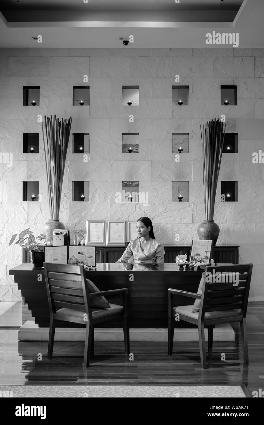 AUG 6, 2014 Hua Hin, Thailand - Asiatische tropischen Stil Hotel Rezeption mit zeitgenössischen Stühlen und Mitarbeiter, die hinter dem Schreibtisch mit Blume Vasen auf Stockfoto