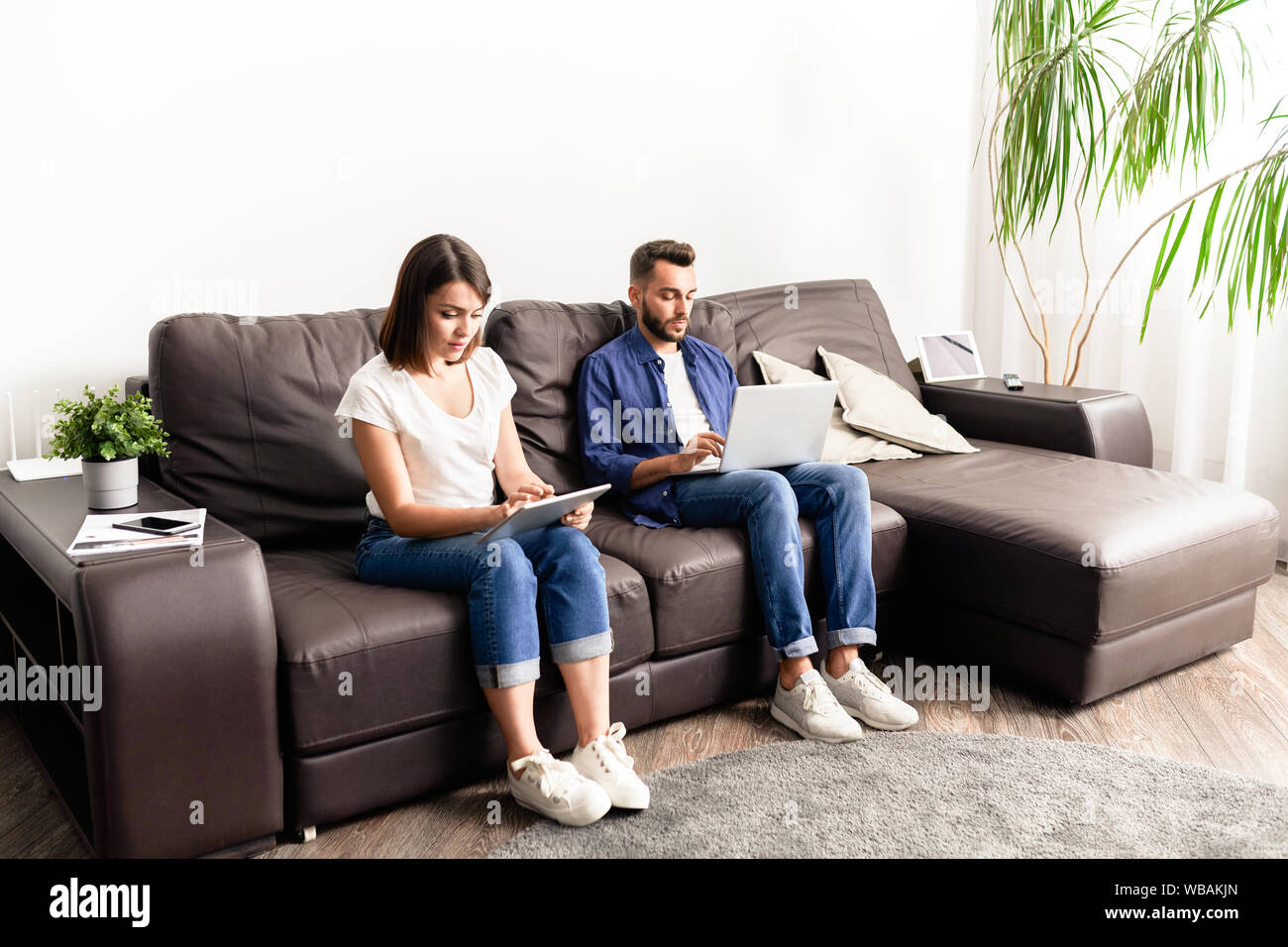 Konzentriert junges Paar in Freizeitkleidung sitzen auf komfortablen Sofa Stockfoto