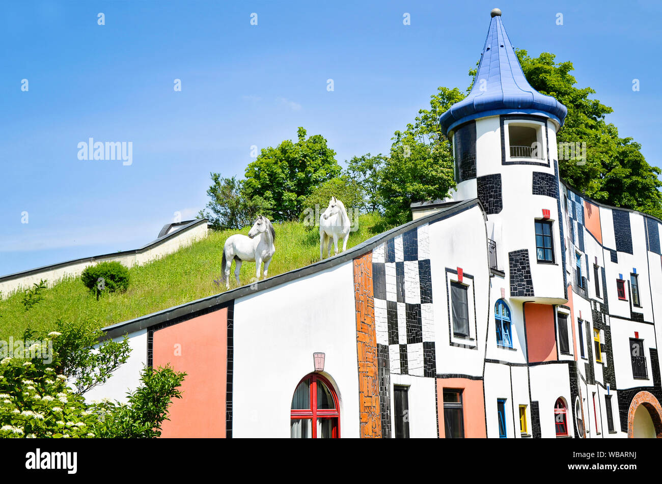 Inländische Pferd. Zwei graue Pferde stehen auf dem Dach des Hotel & Spa Rogner Bad Blumenau (von Friedensreich Hundertwasser gestaltet). Steiermark, Österreich. Stockfoto