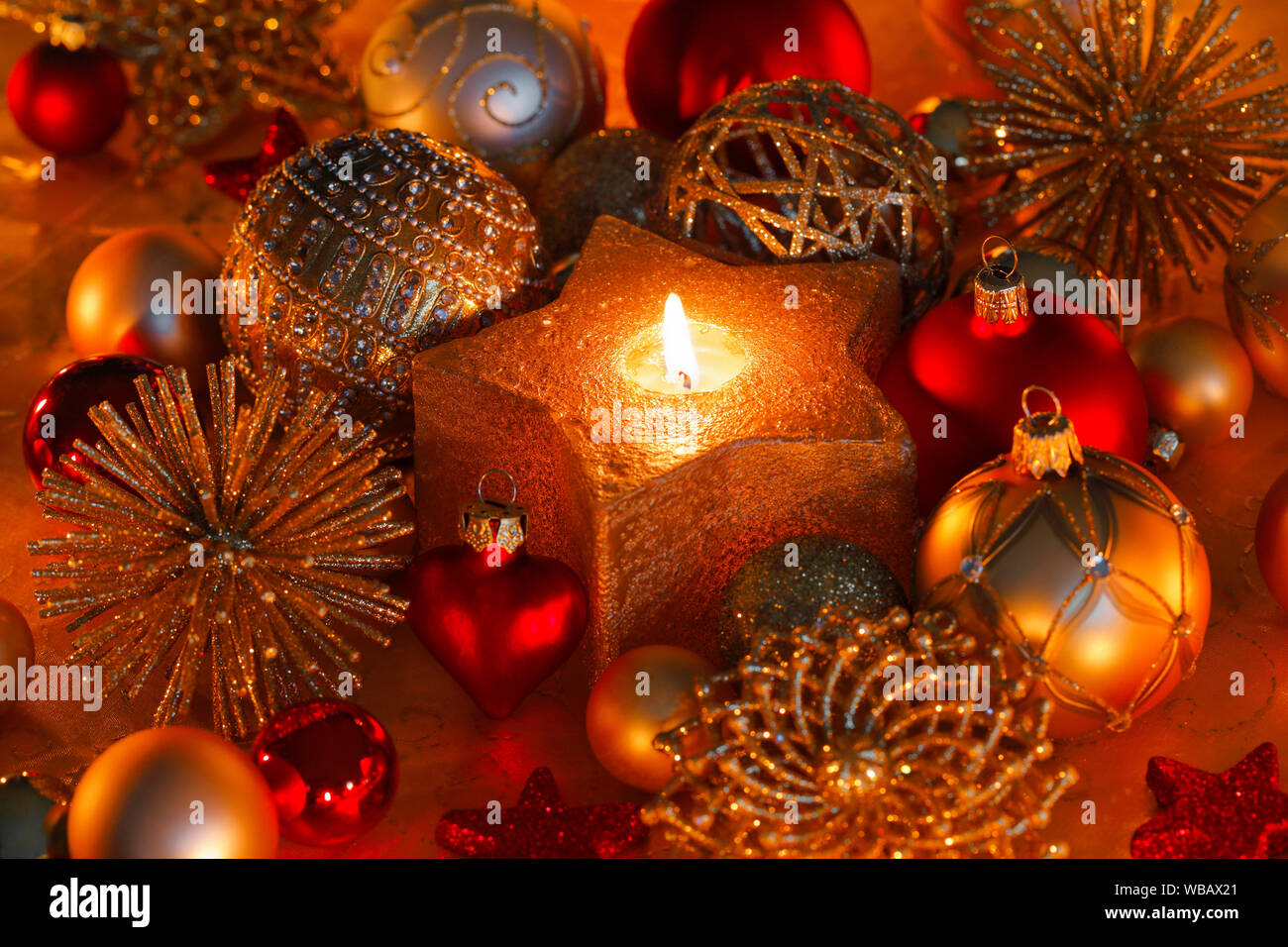 Goldene Weihnachtskugeln und brennenden Teelicht in einem sternförmigen Kerzenhalter. Studio Bild. Schweiz Stockfoto