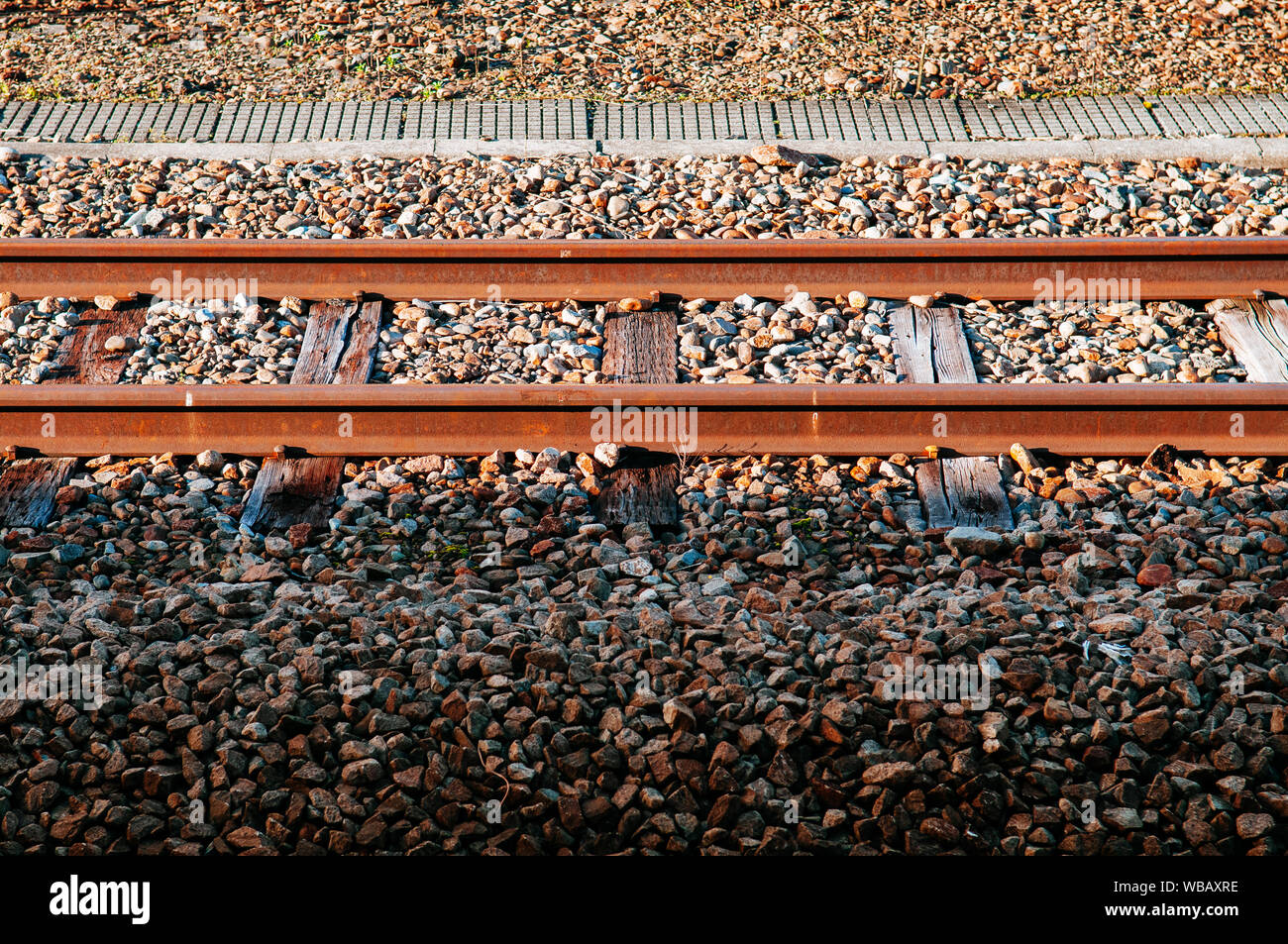 Alte grungy rusty Railway Track mit crosstie aus Holz und Stein unter Sonnenlicht mit einem Teil im Schatten Stockfoto