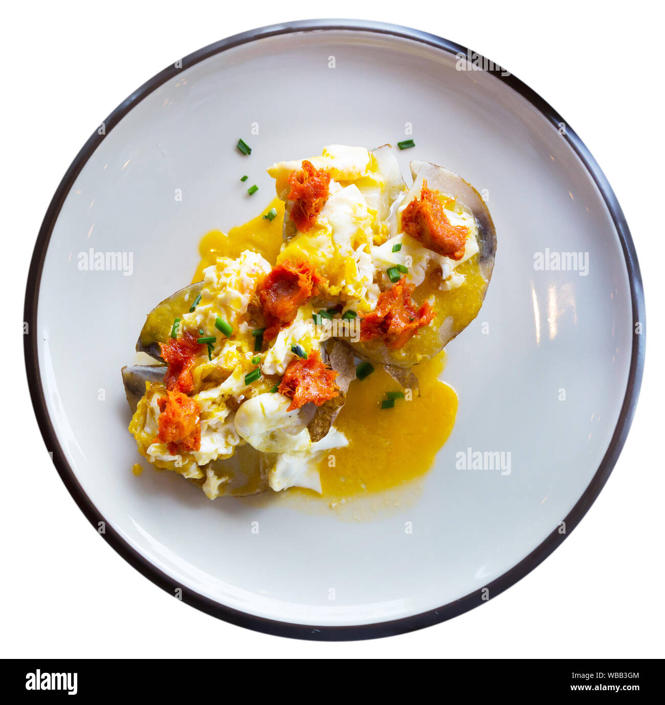 Blick von oben auf die gebackenen Al caliu Kartoffeln mit sobrassada und Spiegelei. Traditionelle spanische Küche. Auf weissem Hintergrund Stockfoto