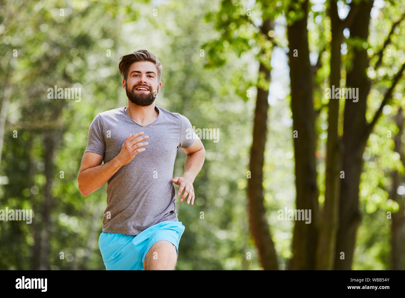 Glückliche junge Mann Joggen im Freien in einem Park im Sommer Stockfoto