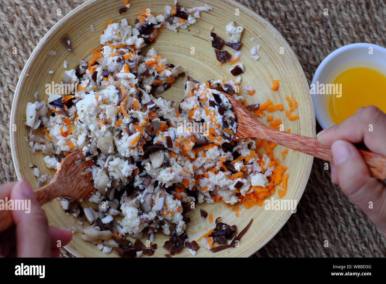 Ansicht von oben hausgemachte Speisen auf Sackleinen, Hintergrund, Frau Hand mix Rohstoffe für vegetarisches Gericht von Pilz, Tofu, Karotte, Ei, vegane Wurst Stockfoto