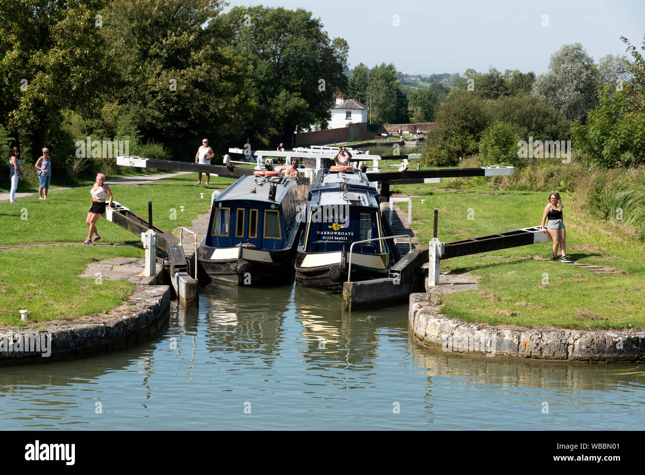 Devizes, Wiltshire, England, UK. August 2019. Zwei narrowboats reisen zusammen durch eine der Sperren auf der Caen Hill Flug von Schlössern. Stockfoto