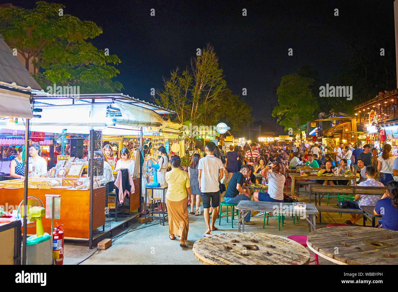 CHIANG MAI, THAILAND - Mai 2, 2019: Die Lounge Zone Plön Ruedee Nachtmarkt mit Tabellen von Kabel rollen und Stühlen inmitten der Essensstände, am 2. Mai i Stockfoto