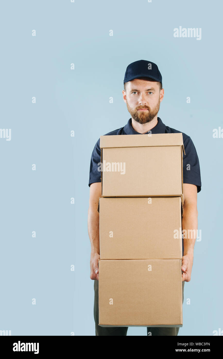 Lieferung Mann in Uniform hält Stapel von Kartons Stockfoto