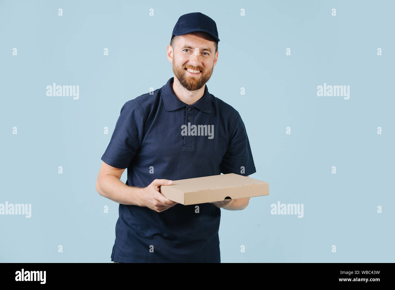 Freundliche Lieferung Mann in Uniform hält Karton pizza box Stockfoto