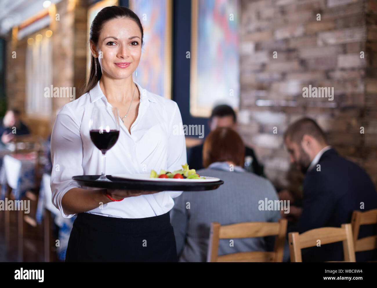 Professionelle happy Kellnerin holding Serviertablett für Gäste Stockfoto