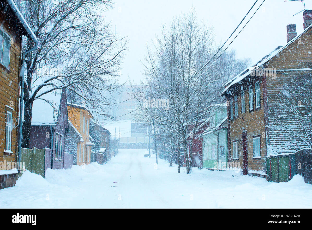 Schneereiche Winter Szene in der Stadt. Schneefall in einer kleinen Straße mit bunten Holzhäusern Stockfoto
