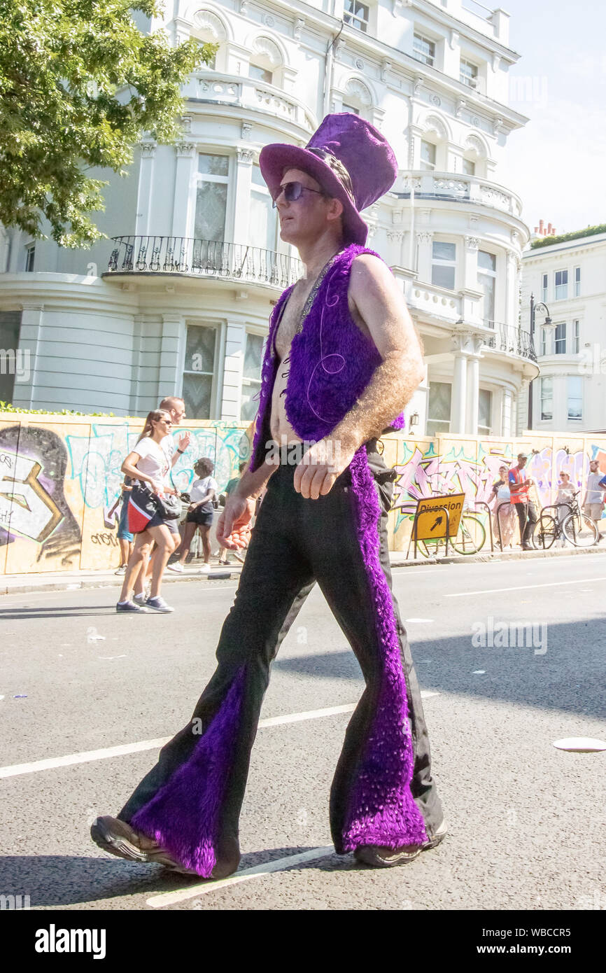 Ein Mann Spaziergänge entlang einer Straße in sein Kostüm. Die wichtigsten Ereignisse der Notting Hill Carnival 2019 erhielt unterwegs am Sonntag, mit über einer Million revellers schlagen die Straßen von West London, unter den Schwimmern, maskierten, Steel Bands und Sound Systeme. Stockfoto