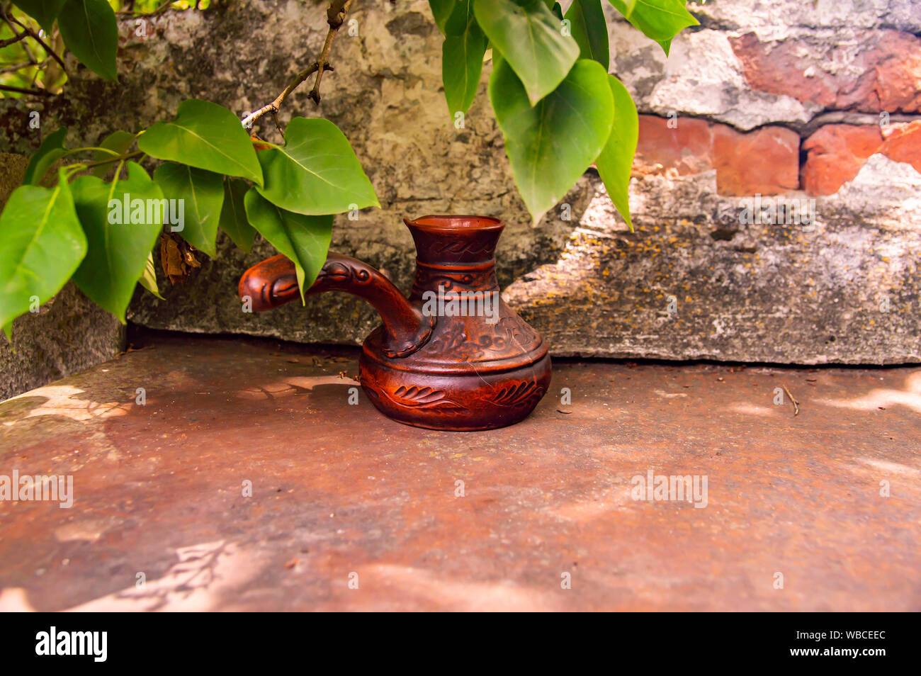 Ton Turk für Kaffee auf einer Ziegelwand Hintergrund. Hintergrund. Stockfoto