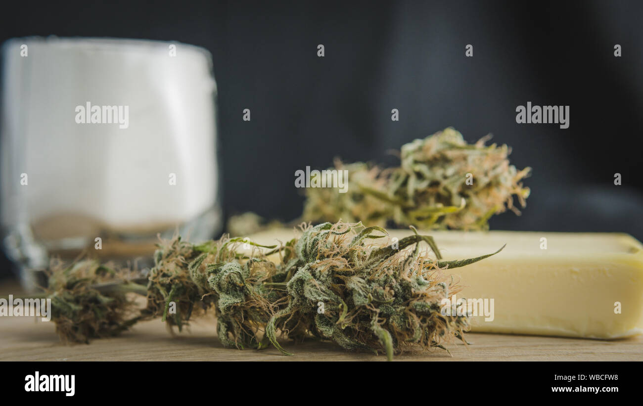 Vorbereitung zum Kochen Kuchen mit Cannabis Butter. Konzept der Verwendung von Marihuana in der Lebensmittelindustrie. Kuchen mit CBD Cannabis und Knospen von Marihuana auf dem Tisch Stockfoto