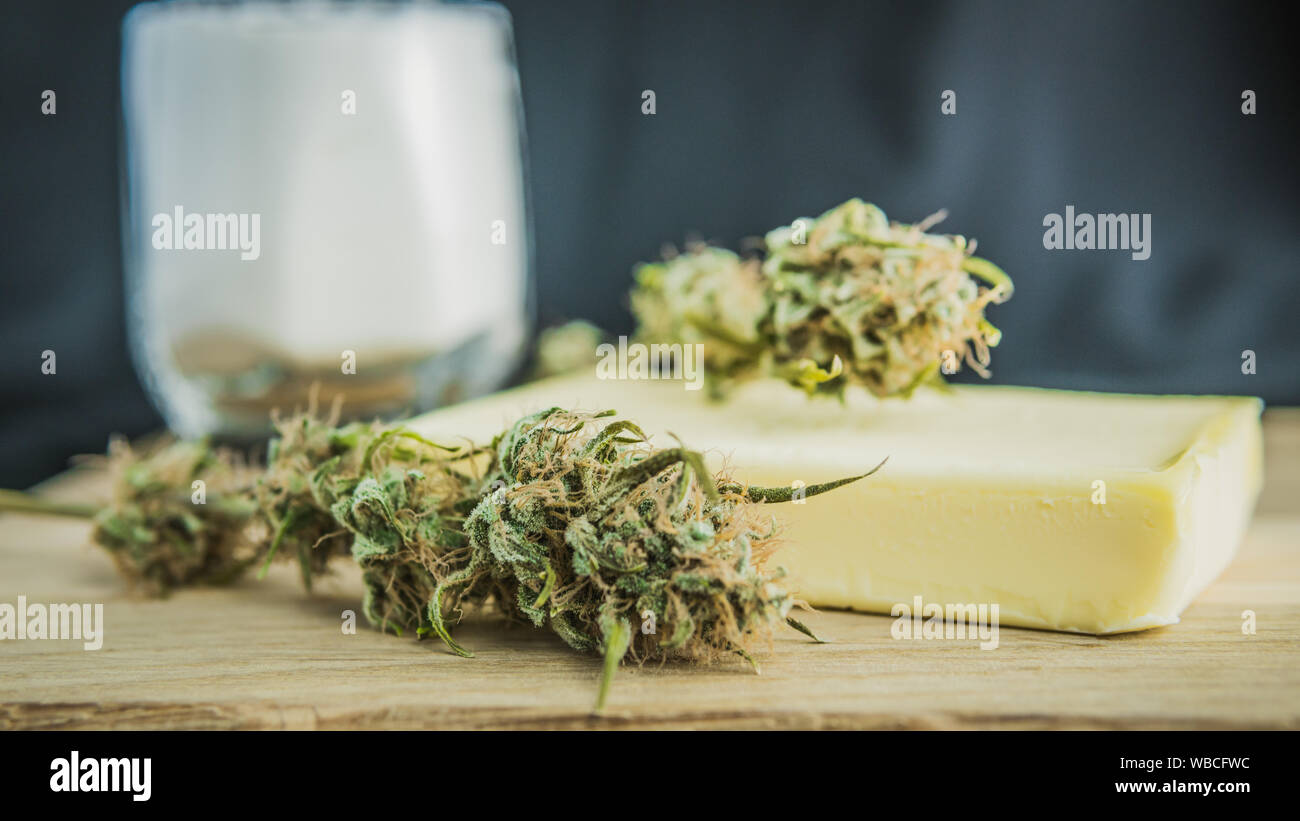 Vorbereitung zum Kochen Kuchen mit Cannabis Butter. Konzept der Verwendung von Marihuana in der Lebensmittelindustrie. Kuchen mit CBD Cannabis und Knospen von Marihuana auf dem Tisch Stockfoto