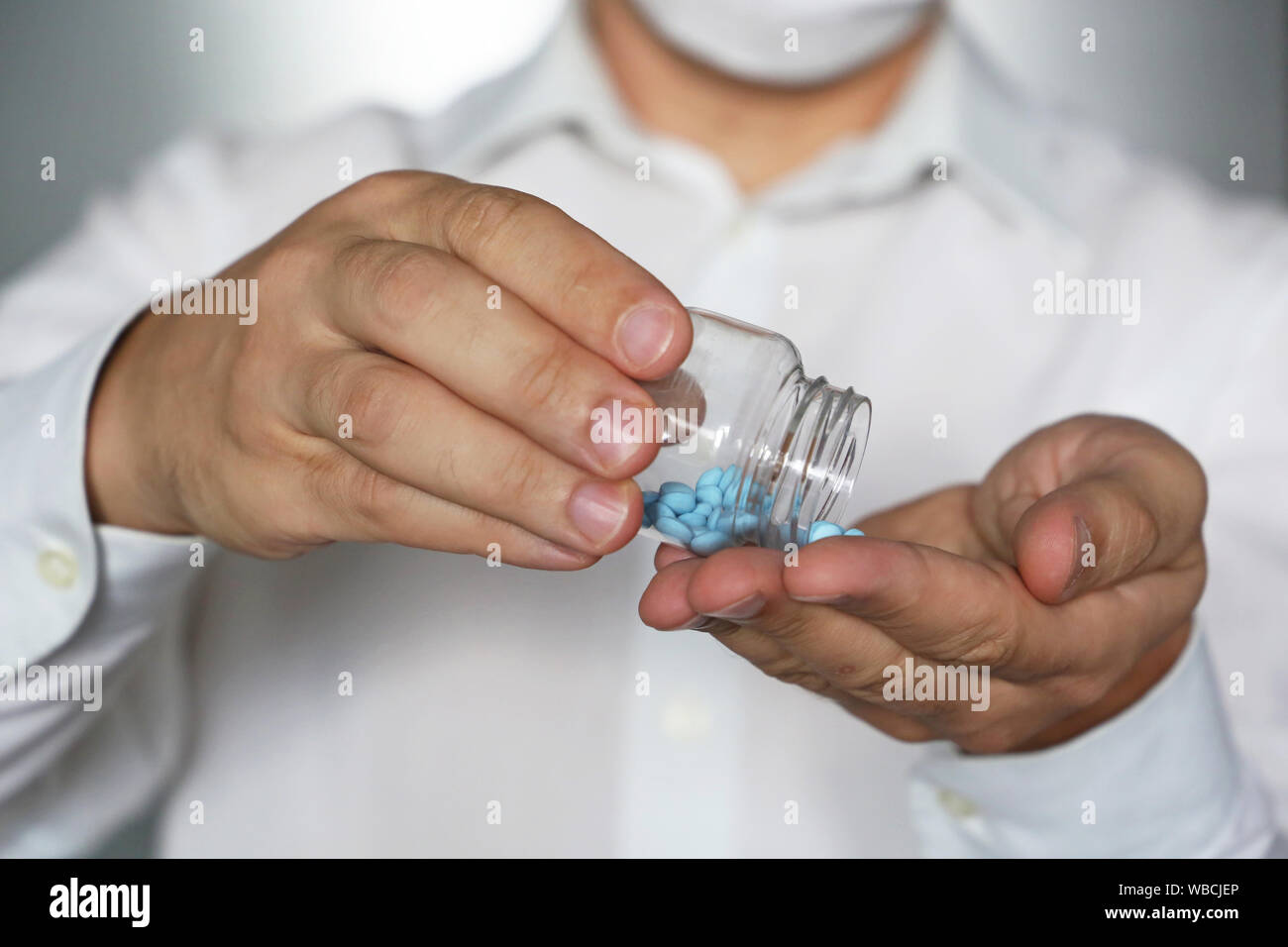 Arzt, Pillen, Arzt in der medizinischen Maske Holding in den Händen Flasche mit blauen Tabletten. Konzept der Dosis von Medikamenten, Vitaminen, Viagra, Apotheke Stockfoto