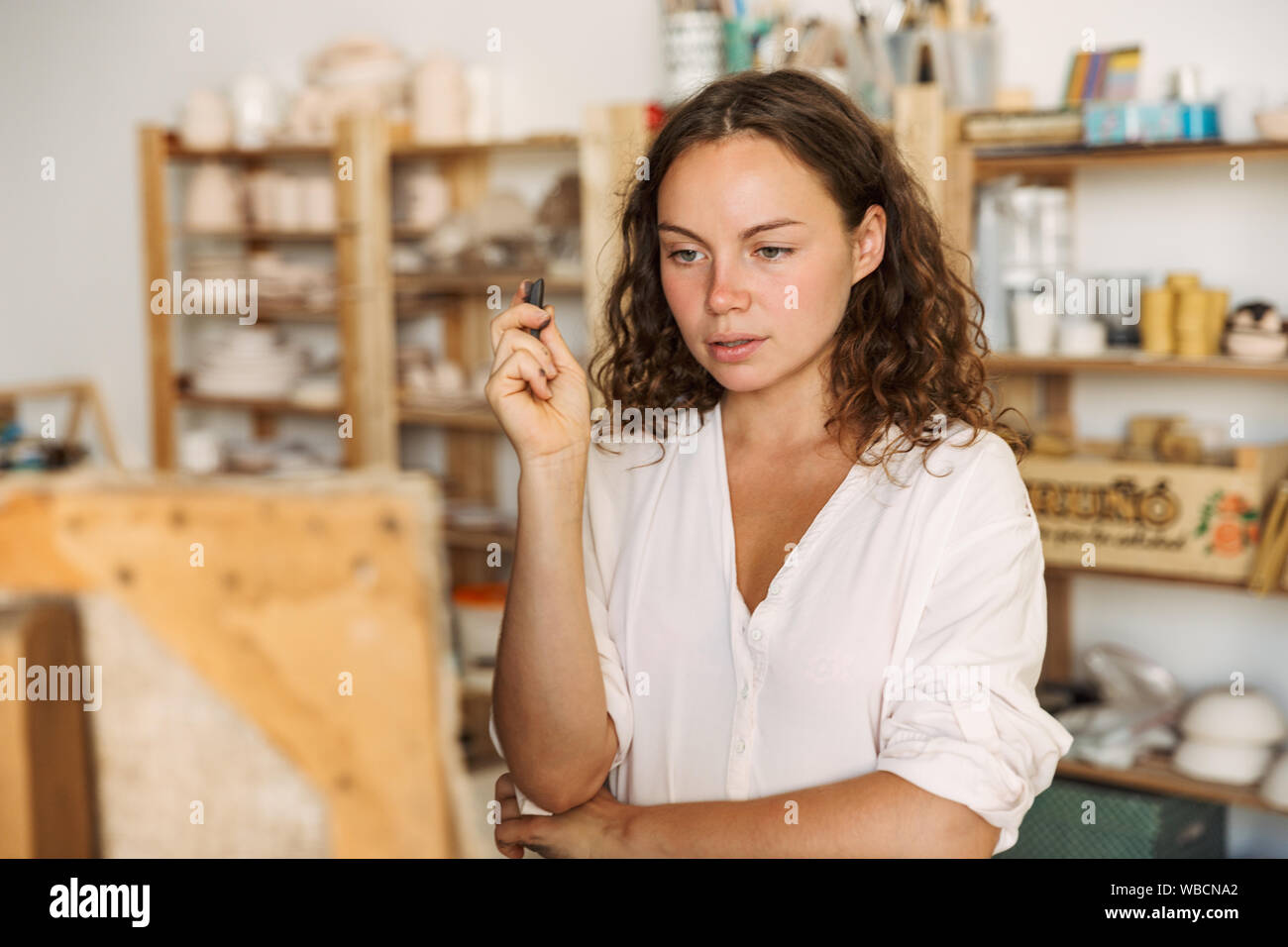 Portrait von nachdenklich konzentriert künstlerische woman holding Stück Kreide beim Zeichnen Bild auf Leinwand in Werkstatt oder Master Klasse Stockfoto