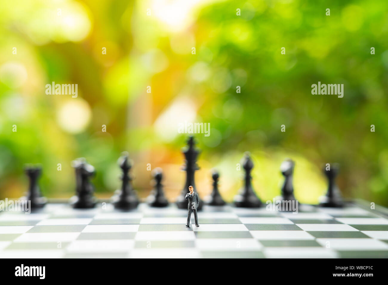 Miniatur Geschäftsleute stehen auf einem Schachbrett mit einer Schachfigur auf dem Rücken. Als Hintergrund Business Konzept mit kopieren. Stockfoto