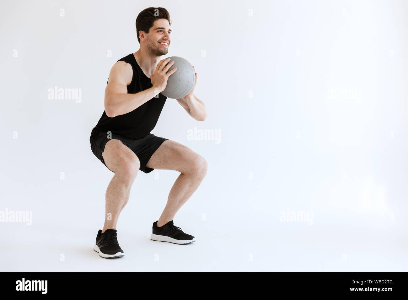 Foto von einem schweren starken jungen Sport Mann hockt Übung mit Ball auf weißem Hintergrund. Stockfoto