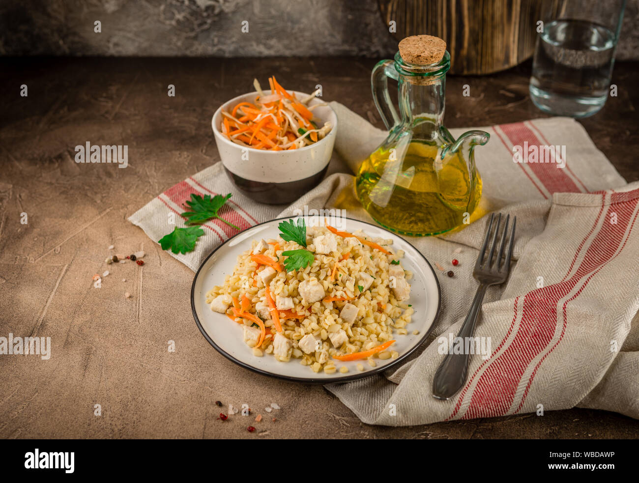 Bulgur Pilaw mit Huhn in einen Teller und eine Schüssel Krautsalat auf braunem Hintergrund konkrete Stockfoto