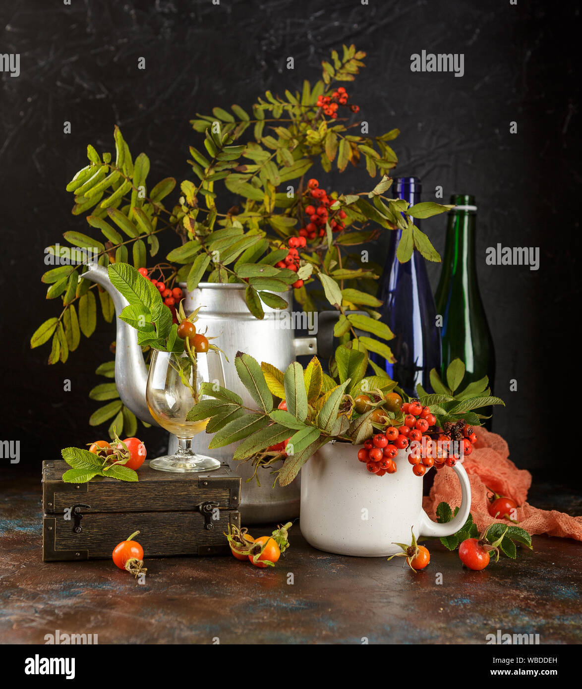 Rowan Niederlassungen in Metall alte Kaffeekanne und in Schale und dogrose Beeren auf dunklem Hintergrund Stockfoto