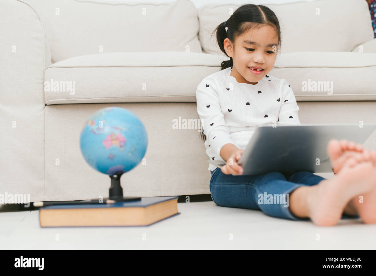 Gerne asiatische Mädchen mit Laptop, Konzept für Kid's Kunst und Home Schule. Stockfoto