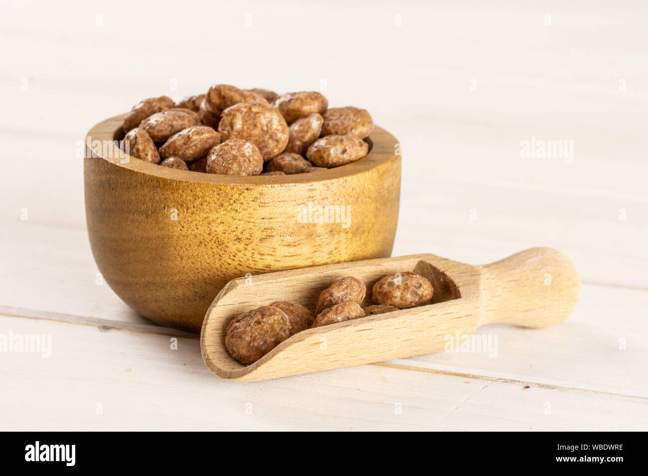 Menge ganze Schokolade Kugel Frühstückszerealien in Houten mit Holz- Schaufel auf weißem Holz Stockfoto