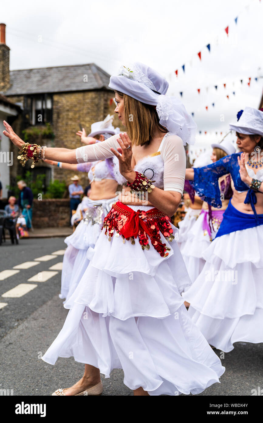 Sandwich Folk und Ale-Festival. Reife Frauen des Gutes Karma Damen Bauchtänzerinnen Tanz draußen auf der Straße in weißen Kleidern und Hüten. Stockfoto