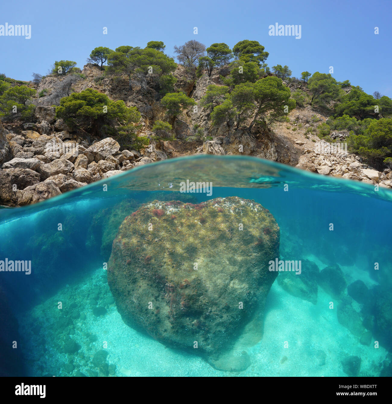 Spanien, Costa Brava, felsige Küste mit einem großen Felsen unter Wasser, geteilte Ansicht oberhalb und unterhalb der Wasseroberfläche, Mittelmeer, Rosen, Katalonien Stockfoto
