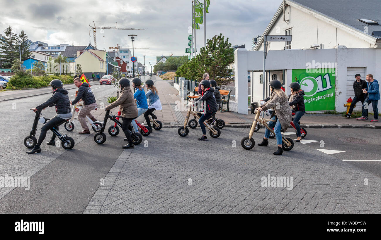 Leute, Touristen, Motorroller oder Fahrräder im Einkaufsviertel in Reykjavik, Island. Stockfoto