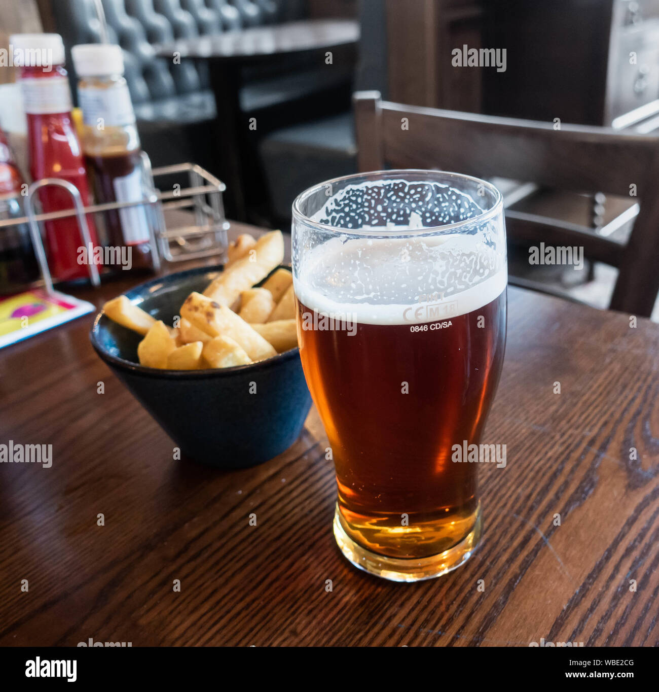 Ein Pint Bier und Schüssel von Chip/Pommes frites in JD Wetherrspoon Pub. Großbritannien Stockfoto