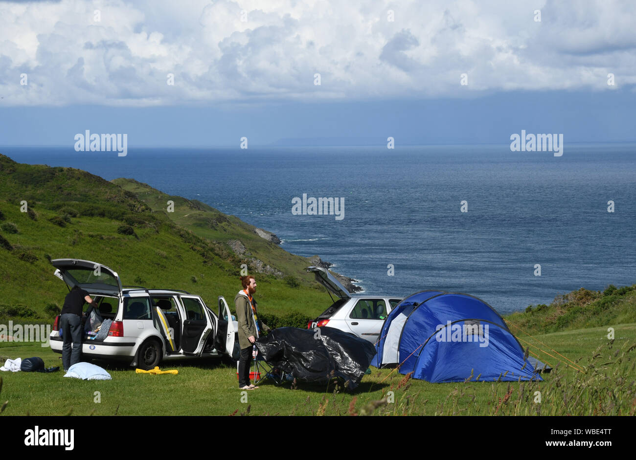 Zögern Camper bis Verpackung thier Zelte und Ausstattung auf einem schönen Campingplatz mit Blick auf das Meer in North Devon, England, Großbritannien Stockfoto