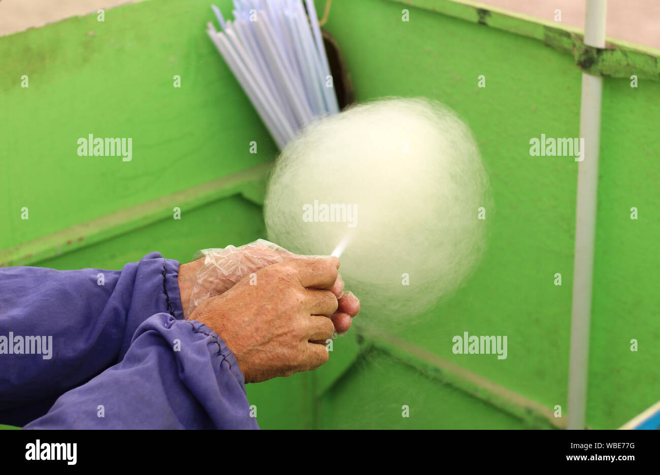 Hausgemachte Prozess, Zuckerwatte. Hände von einem alten Mann mit einem Stock mit Zuckerwatte Stockfoto