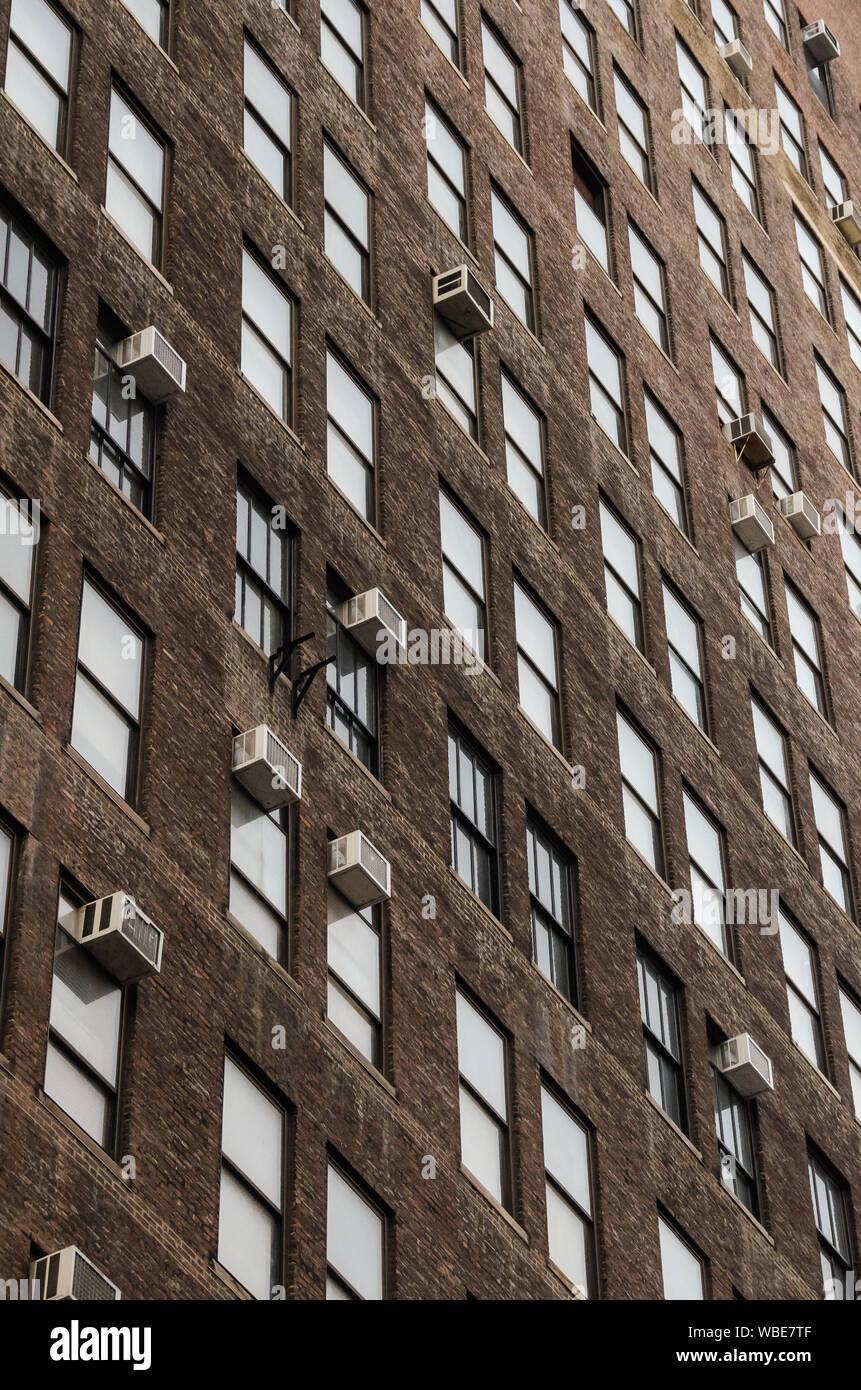 Vertikale Ansicht von geometrischen generische Windows und Klimaanlage Geräte auf einer industriellen Backsteingebäude in der Morgendämmerung in den Vereinigten Staaten Stockfoto