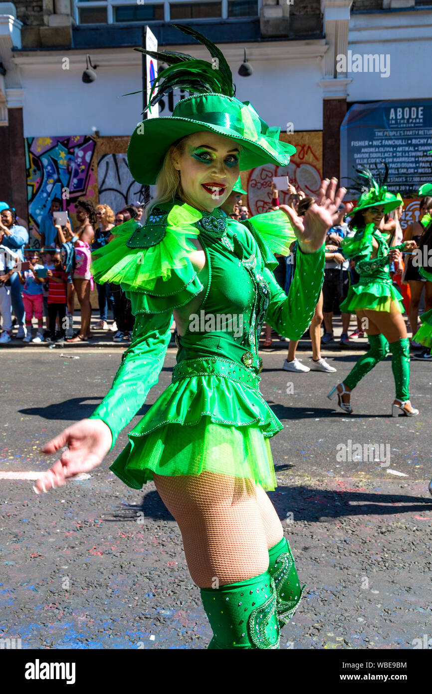 26. August 2019 - Tänzerin in einem grünen Kostüm und Hut mit Federn gekleidet in Notting Hill Karneval an einem heißen Feiertag Montag, London, UK Stockfoto