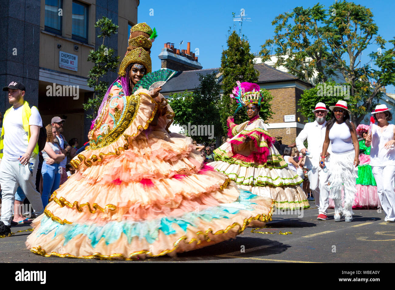 26. August 2019 - die Frau, die in einem langen Kleid mit Reifrock und kunstvollen Kopfschmuck am Notting Hill Carnival an einem heißen Feiertag Montag, London, UK Stockfoto