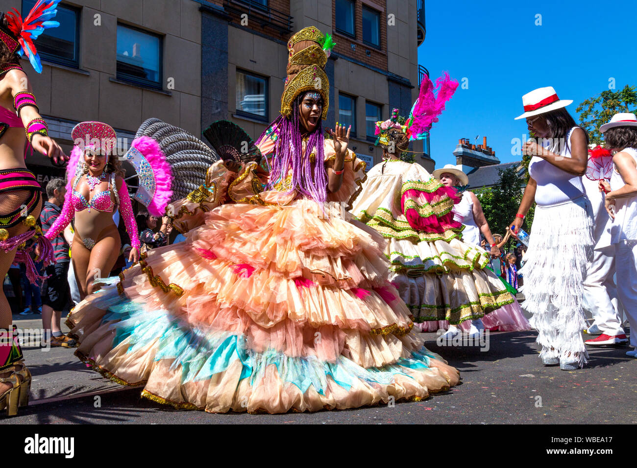26. August 2019 - die Frau, die in einem langen Kleid mit Reifrock und kunstvollen Kopfschmuck am Notting Hill Carnival an einem heißen Feiertag Montag, London, UK Stockfoto