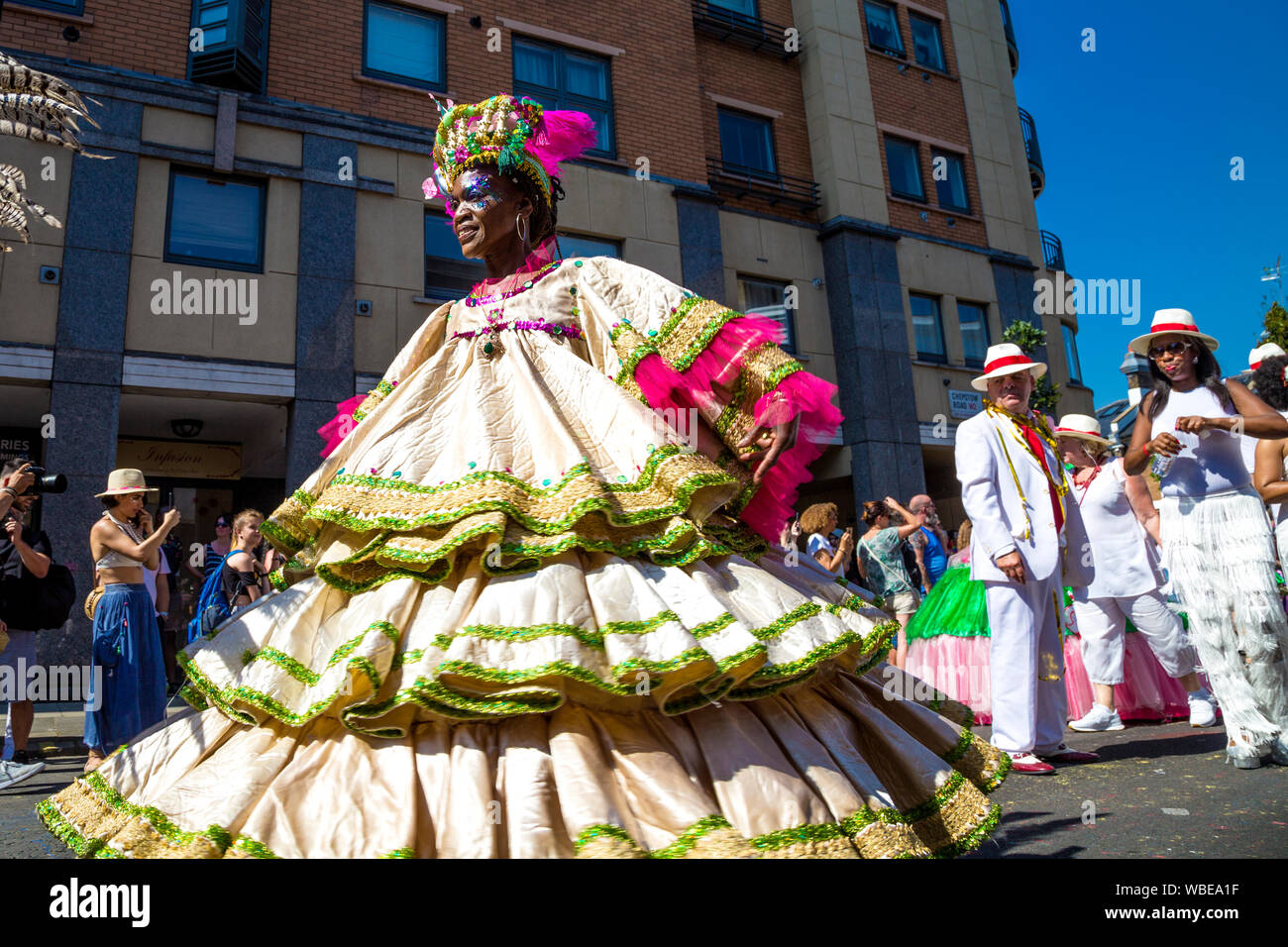 26. August 2019 - Tänzerin tragen ein großes Kleid und Kopfbedeckung in Notting Hill Karneval an einem heißen Feiertag Montag, London, UK Stockfoto