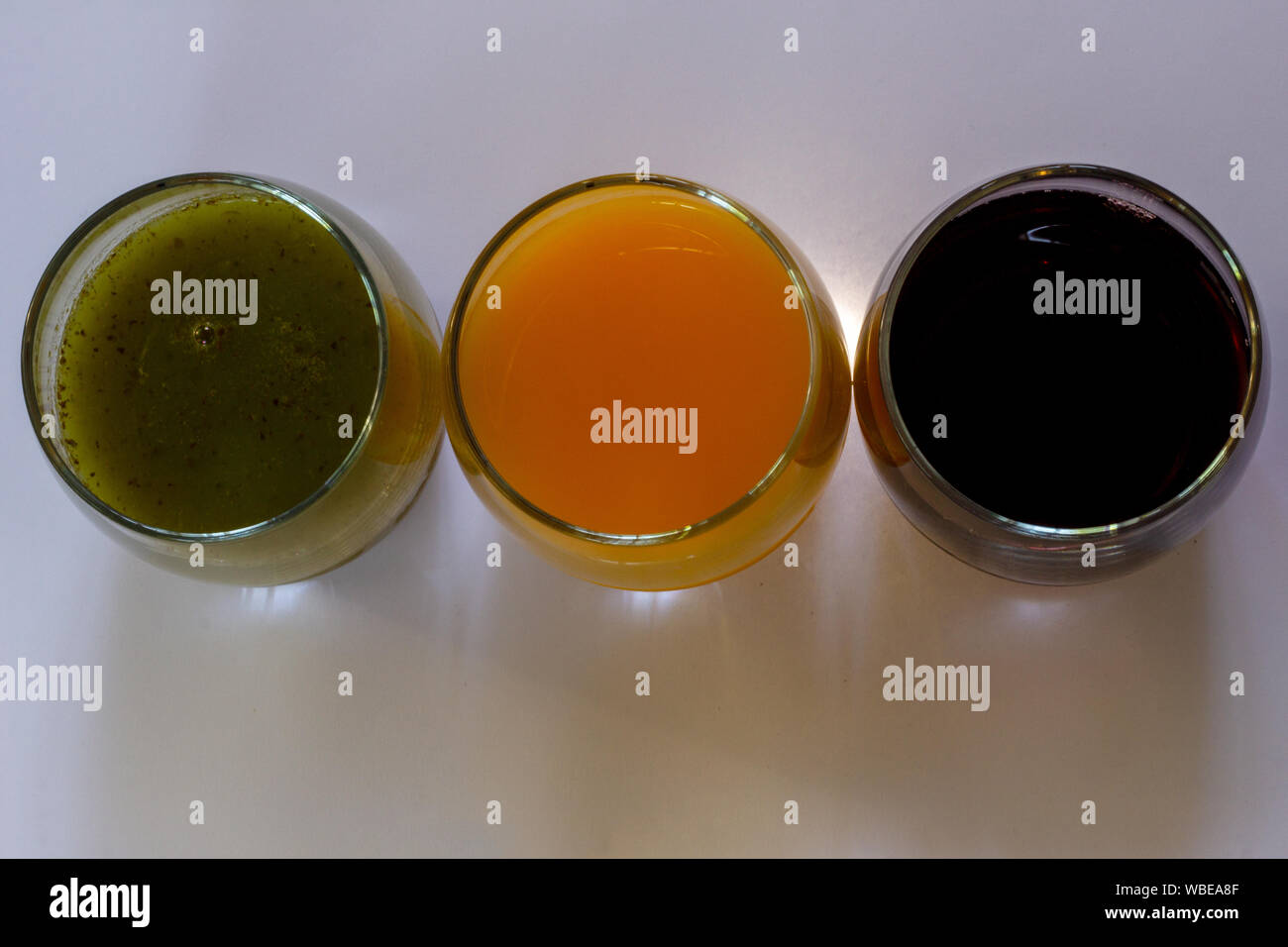 Ansicht von oben von drei Gläser mit Traubensaft rot gesäumt, Orangensaft und grünes Gemüse Saft in Ampel Sequenz Stockfoto