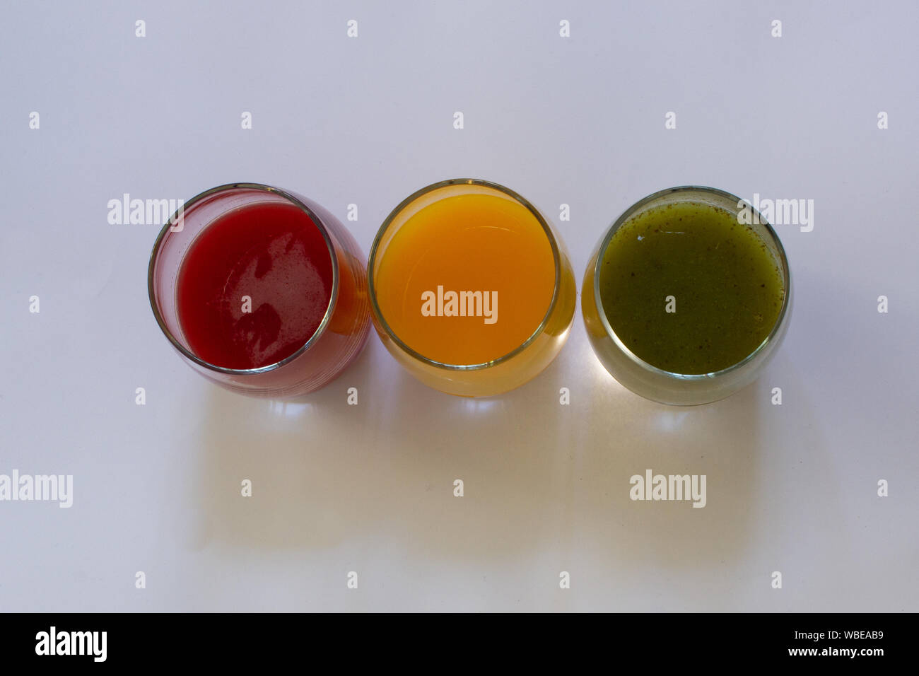 Ansicht von oben von drei Gläser mit Traubensaft rot gesäumt, Orangensaft und grünes Gemüse Saft in Ampel Sequenz Stockfoto