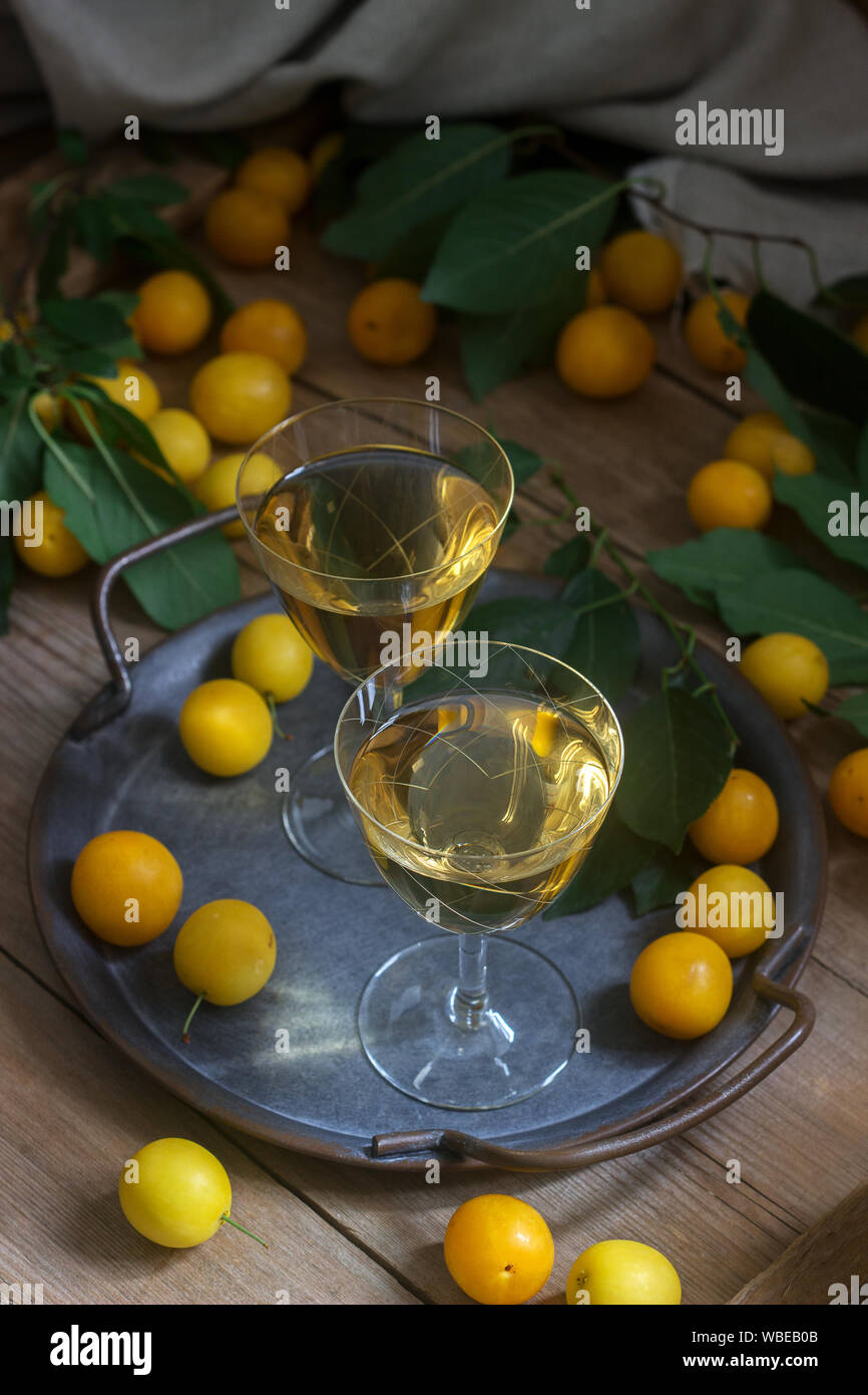 Cherry Plum Likör in kleinen Gläsern und Cherry Plum auf einer hölzernen Hintergrund. Im rustikalen Stil. Stockfoto