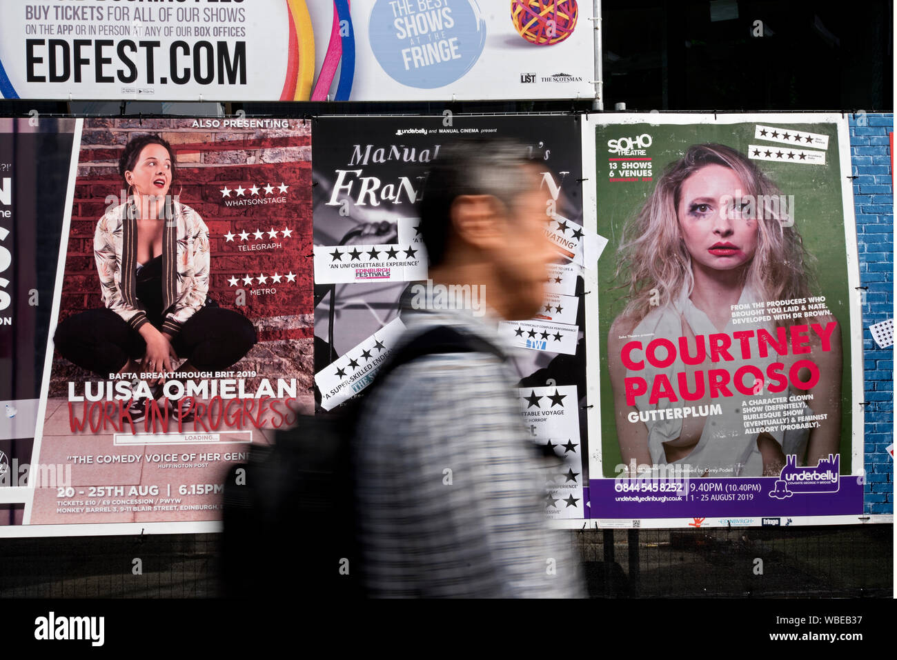 Ein Mann zu Fuß durch Werbeplakate für Edinburgh Fringe Festival zeigt. Edinburgh, Schottland, Großbritannien. (Mit Motion Blur) Stockfoto