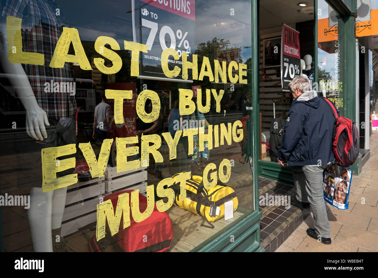 Einem Kunden, der in der Princes Street Zweig der Mountain Warehouse, ein Schild im Fenster: "Letzte Chance, aber, muss alles gehen'. Stockfoto