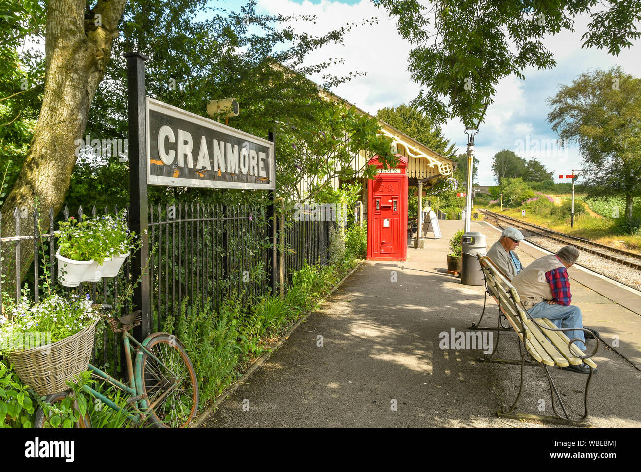 CRANMORE, ENGLAND - Juli 2019: Menschen sitzen auf einer Bank warten auf einen Zug bei Cranmore Station auf der East Somerset Railway. Stockfoto