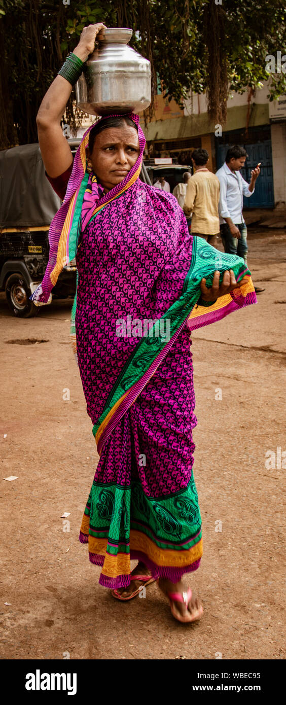 BADAMI, INDIEN, Mar 18, 2018: Frau trägt ihre Last auf dem Kopf Stockfoto