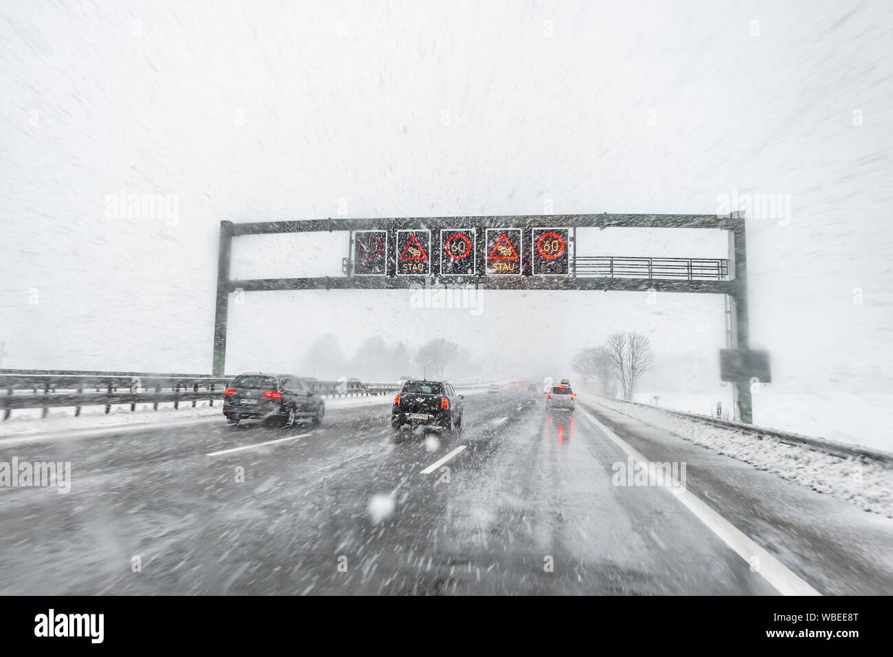 Staugefahr und Geschwindigkeitsbegrenzungen, schlechtes Wetter, Auto Verkehr während starker Schneefall und Regen auf der Autobahn A8, in der Nähe von München, Bayern, Deutschland Stockfoto
